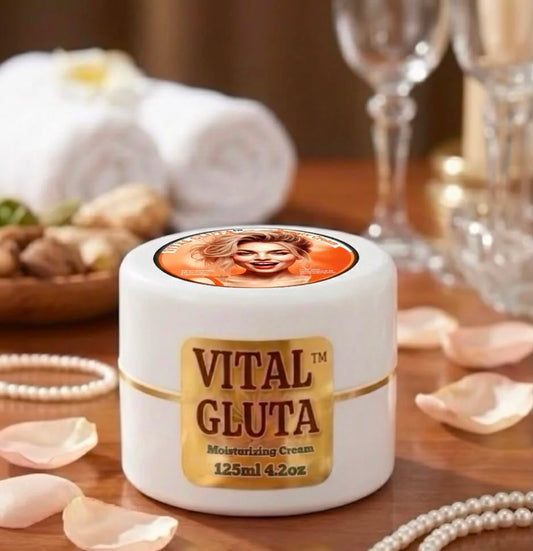 A white jar of VITAL GLUTA Moisturizing Cream with a gold label, set on a wooden table with rolled towels, wine glasses, and pearl strands in the background.